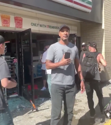 Man standing outside a looted 7/11 helps quiet and calm an angry crowd